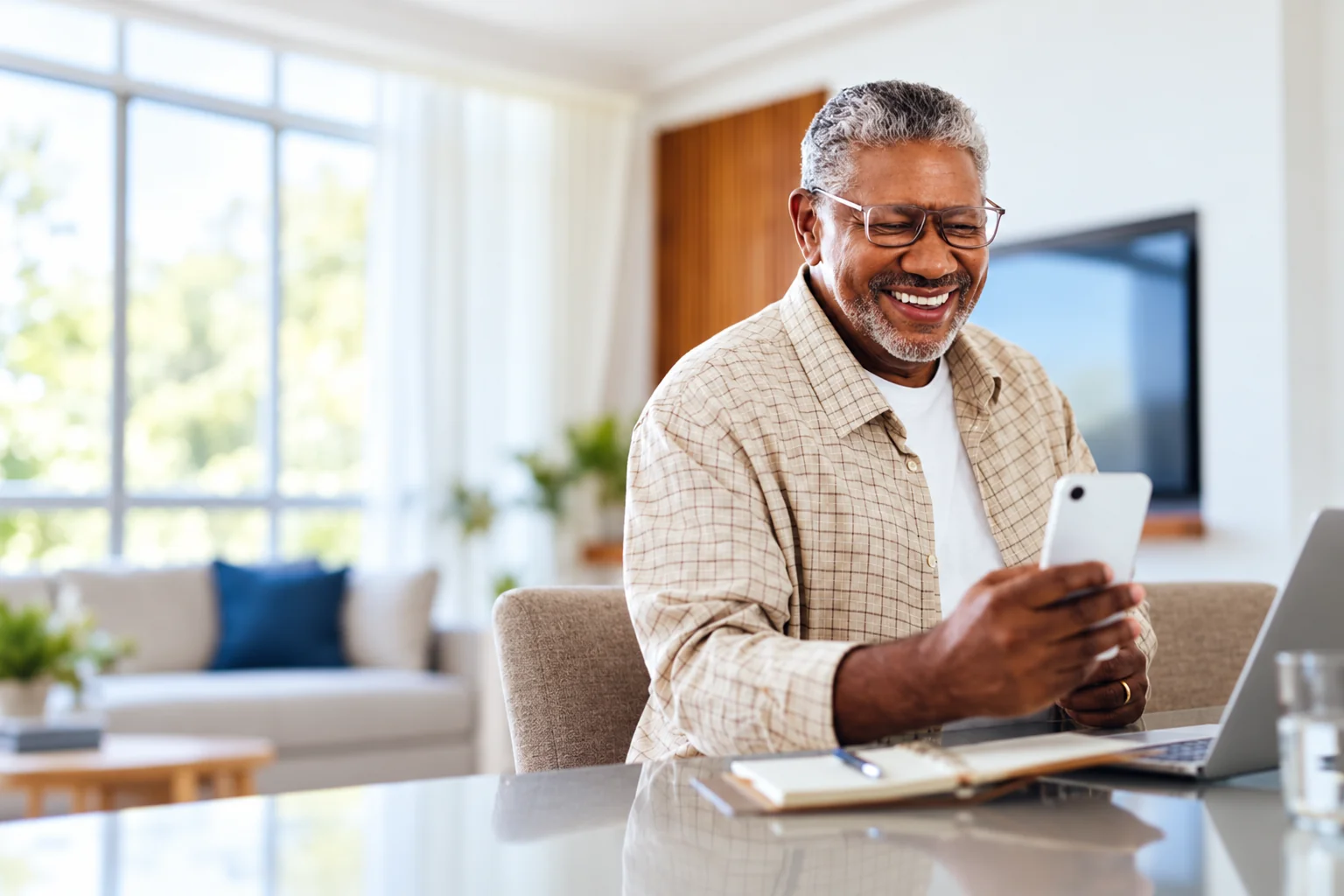 A smiling man using his phone at home